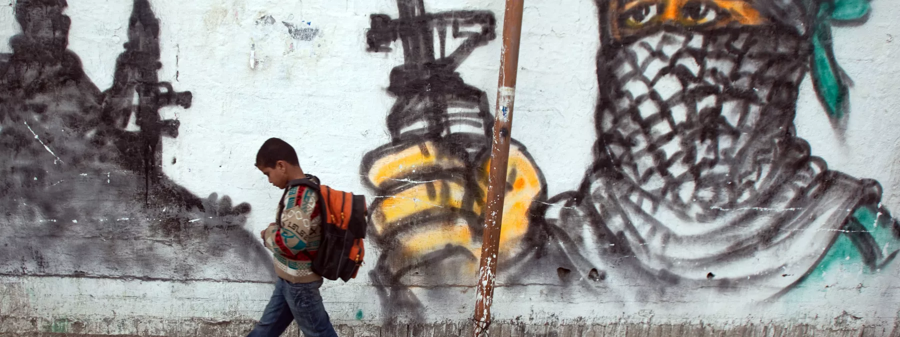 Palestinian boy passing by a grafitti as he walks to school at Jabalia area, northern Gaza Strip